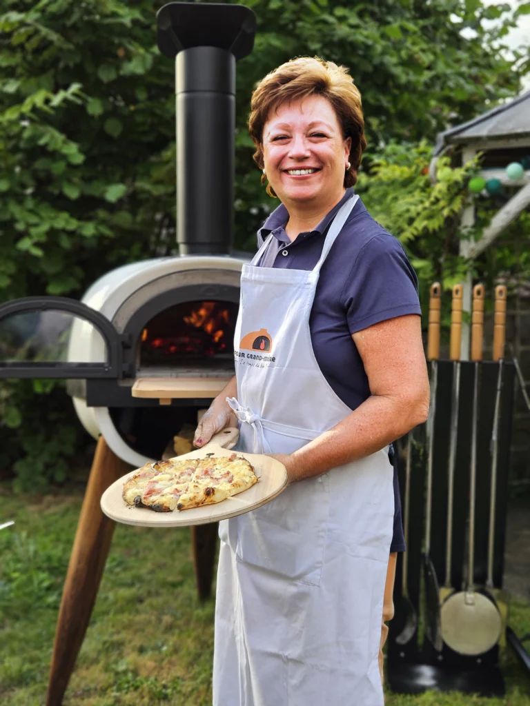 Grand-mère avec une tarte flambée sur une pelle à garnir